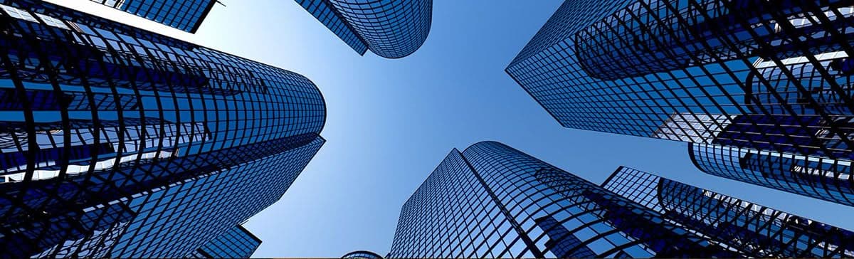 Looking up at glass office towers against a clear blue sky